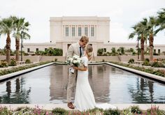 a bride and groom standing in front of a fountain