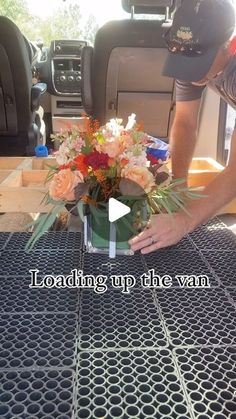 a person placing flowers in a vase on top of a table with the words loading up the van