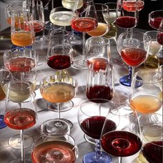 a table topped with lots of wine glasses filled with different types of wines and drinks