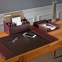 an office desk with a cell phone, pen holder and glasses on top of it