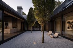 an empty courtyard with benches and trees in the evening