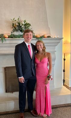 a man in a suit and tie standing next to a woman in a pink dress