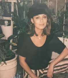 an old photo of a woman sitting in front of potted plants and holding a knife