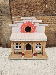 a small wooden house with flowers on the roof