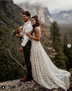 a bride and groom standing on top of a mountain