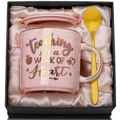 a pink coffee mug with a yellow spoon in it and the words teaching is a work of heart