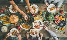 people sitting at a table with plates of food and forks in their hands as they eat