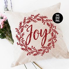 a pillow with the word joy printed on it next to some flowers and a plant