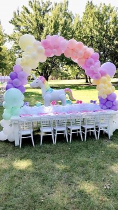 an outdoor table with balloons and unicorns on it