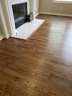 an empty living room with hard wood floors and a fire place in the fireplace mantel