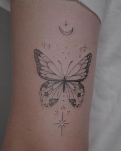 a small butterfly tattoo on the side of a woman's leg with stars and crescent moon