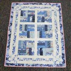 a blue and white patchwork quilt on the floor in front of a carpeted area