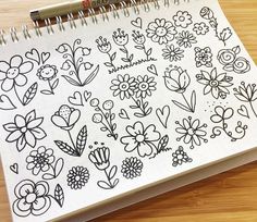 an open notebook with doodled flowers and hearts on the pages, sitting on a wooden surface