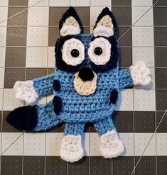 a crocheted blue and white stuffed animal laying on top of a tiled floor