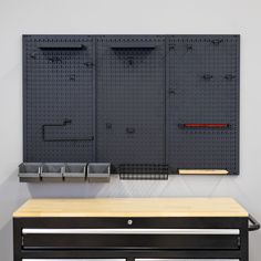 a wall mounted pegboard with hooks and bins on it next to a table