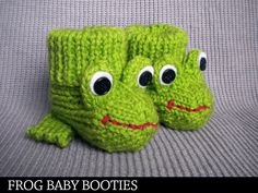 two green crocheted frog baby boots with eyes and mouths, sitting on a gray surface