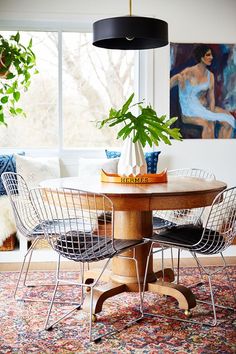 a dining room table with two chairs and a potted plant in the middle on top