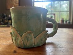 a green mug sitting on top of a wooden table