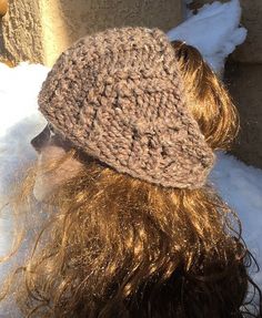 a woman with long hair wearing a crochet hat in the snow, back view