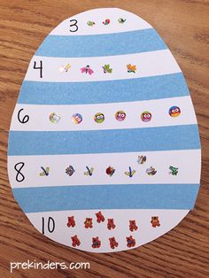 an easter egg with stickers on it sitting on a wooden table next to numbers