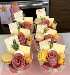 two wine glasses filled with different types of cheese and crackers on top of a table