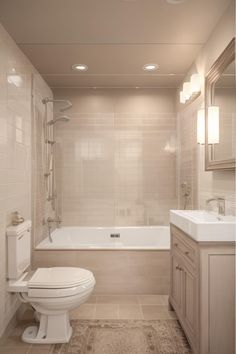 a white toilet sitting in a bathroom next to a bath tub and sink under two lights