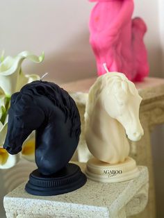 two black and one white horse statues on a table