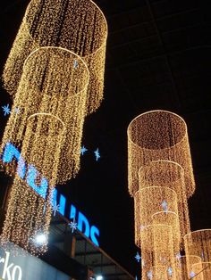 christmas lights are hanging from the ceiling in front of a shopping center sign at night