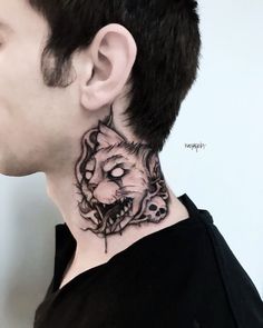 a man with a tattoo on his neck has a tiger head and skull in the middle