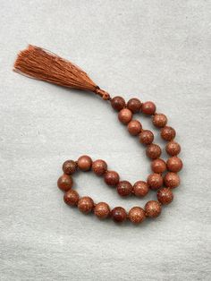 Gold Sandstone Beads is a perfect for Healing, Jewelry & Gift. Healing with Gold Sandstone ♥ Vitality ♥ Drive ♥ Ambition Beads In Mala - Gold Sandstone Necklace Length - 10-12 Inches Handmade Tassel - 2 Inches Beads Size - 8mm Goldstone is said to be the stone of ambition.  It builds energy, courage and a positive attitude.  Increases drive and confidence.  A gently uplifting stone, Goldstone promotes vitality. Goldstone helps to reduce stomach tension and benefits arthritic conditions.  It is helpful to bones, painful joints and circulation. This pocket Mala is made with Gold Sandstone beads. It consists of 27 beads plus 1 Guru bead, hand knotted for strength and flexibility. This pocket Mala is not designed to be worn but rather keep in your pocket for those who are not allowed to wear a Brown 8mm Round Beads, Brown 8mm Beads, Brown Beaded Necklaces With 8mm Beads, Brown Beaded Necklace With 8mm Round Beads, Sandstone Necklace, Mala Jewelry, Attitude Positive, Mala Meditation, Meditation Beads