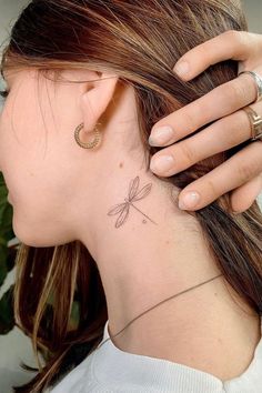 a woman with a small dragonfly tattoo on her back neck and behind her ear