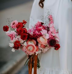 a woman holding a bouquet of pink and red flowers