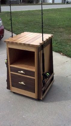 a wooden cabinet with two fishing rods on it's top and bottom drawers, sitting in the middle of a sidewalk