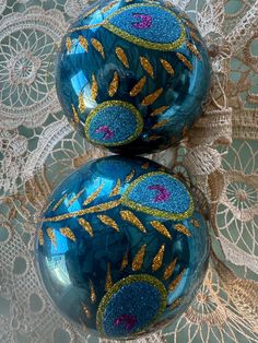 two blue and gold ornaments sitting on top of a doily