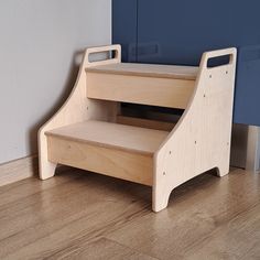 a wooden step stool sitting on top of a hard wood floor next to a blue wall