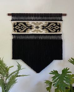 a black and white wall hanging next to a potted plant