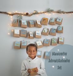 a young boy standing in front of a wall with christmas cards hanging from it's sides