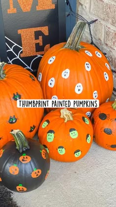 several pumpkins with faces painted on them are sitting in front of a sign that says, thumppint painted pumpkins