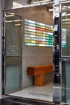 a bench sitting in front of a glass wall with books on it's sides