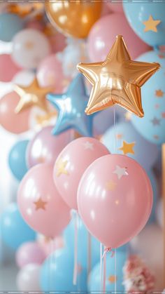 balloons and stars hanging from the ceiling in front of blue, pink, and gold balloons