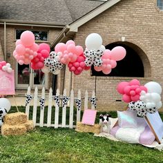 some pink and white balloons are in front of a house with black and white decorations