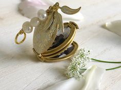 a white flower and some gold jewelry on a table