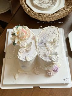 there is a cake that looks like a butterfly on top of a plate with flowers