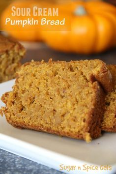 two slices of pumpkin bread on a white plate with oranges in the background and text overlay that reads sour cream pumpkin bread