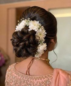 a woman with flowers in her hair wearing a pink dress and holding a white flower in her hair