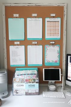 a desk with a monitor, keyboard and other office supplies on it next to a cork board