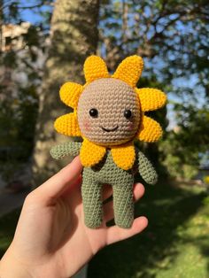 a small crocheted sunflower is held in the palm of someone's hand