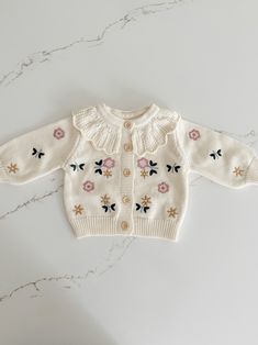 This Knit Floral Cardigan is perfect for your little one! With its intricate floral embroidery and dainty little buttons, your baby will be lookin' cute as a button. And the ruffled hollow collar? Beyond adorable! Keep your little bloom at the height of fashion with this cozy knit cardigan. Spring Cotton Cardigan For Playtime, Cute Cream Cotton Cardigan, Spring Long Sleeve Cardigan For Playtime, Cute Embroidered Cotton Cardigan, Spring Playtime Long Sleeve Cardigan, Cute Spring Cardigan For Playtime, Cute Cotton Cardigan With Button Closure, Cotton Cardigan With Button Closure, Cute Style, Cute Spring Sweater For Playtime