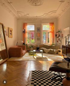 a living room filled with lots of furniture next to a window covered in orange curtains