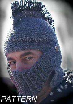 a man wearing a crocheted knit hat with pom - poms on his face